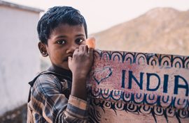 A young boy standing beside a large painted wall sign