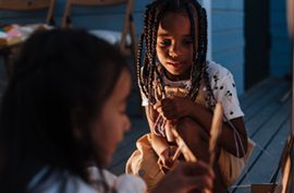 Two children playing together indoors by warm lamplight