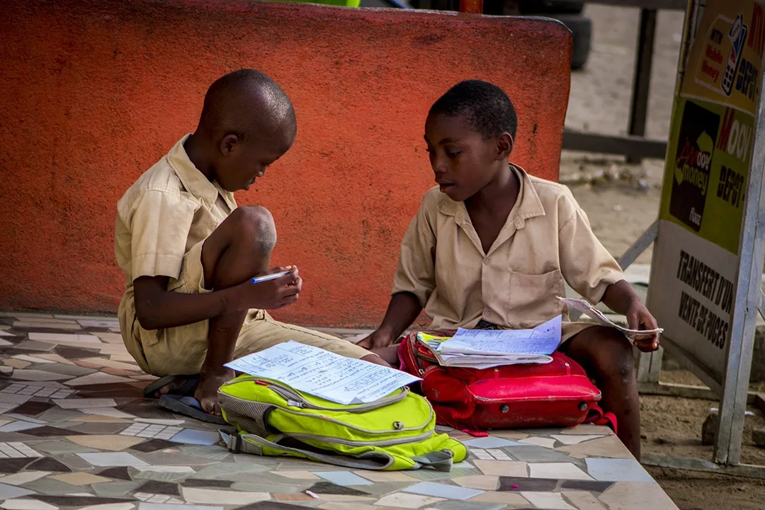 Two schoolboys studying outdoors, supported by the Oloowere Foundation