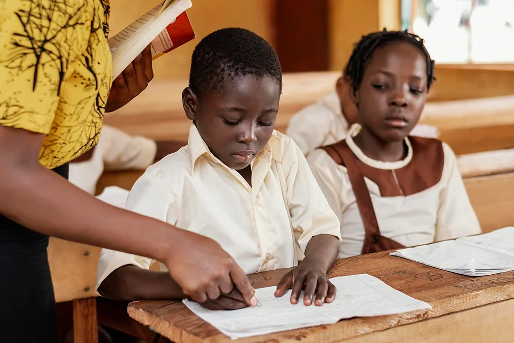 Teacher guiding two pupils, one of the student stories behind the Oloowere Foundation